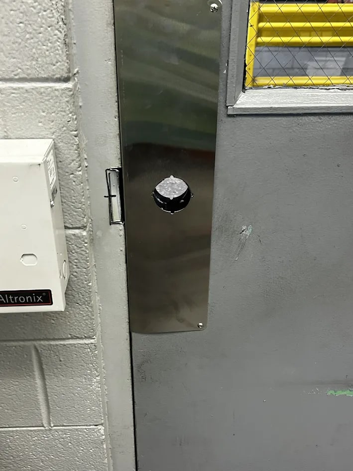 Steel door finished with a long satin stainless plate at the latch position and a black round knob fitted through it