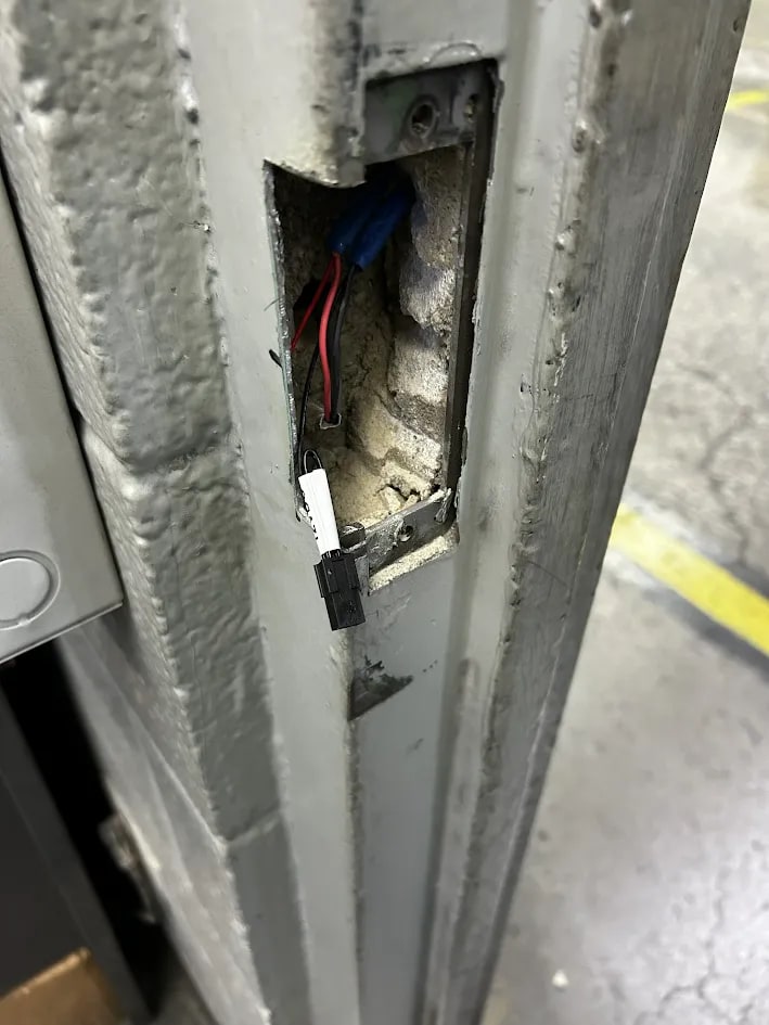Close view of the jamb aperture with red and black conductors terminating in a white plug connector