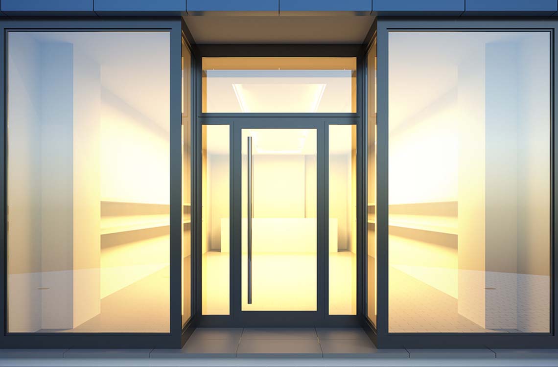 Empty glass storefront entrance with dark metal frames and a vertical pull handle