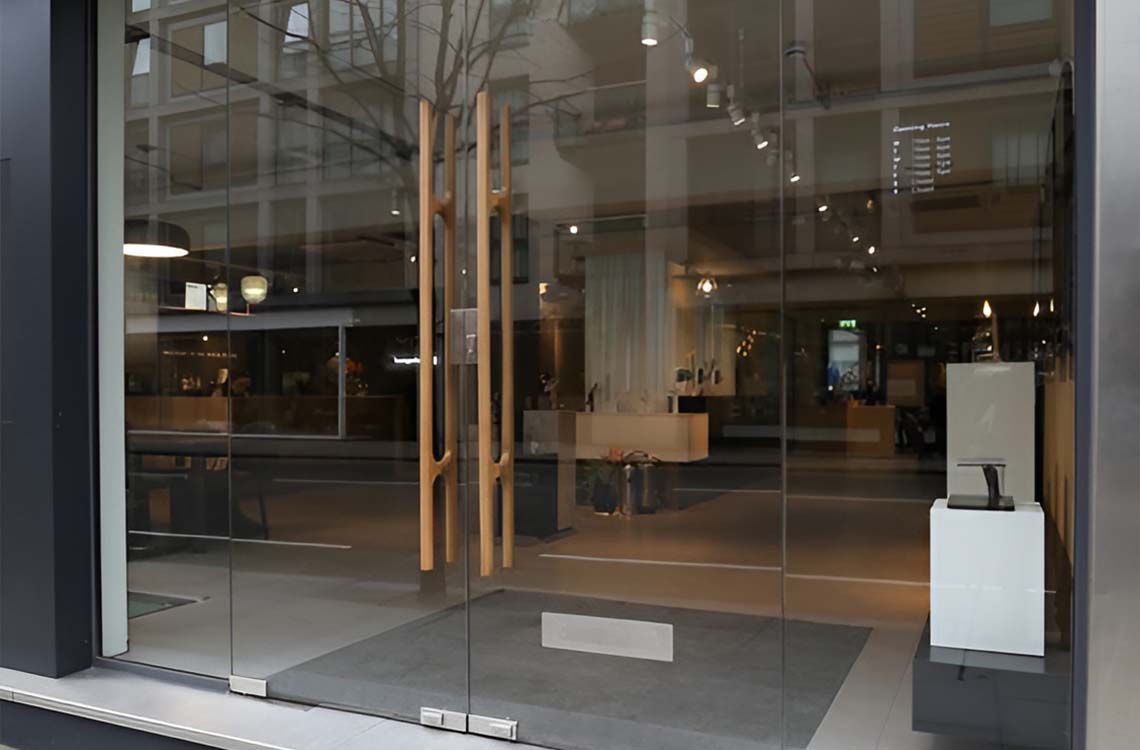 Frameless glass storefront entry doors with tall vertical wooden pull handles