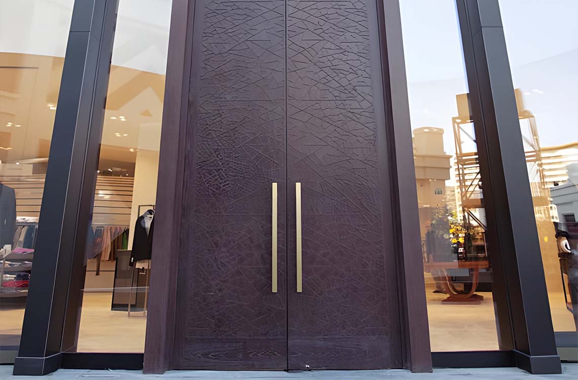 Dark wood double entry doors with etched leaf pattern and brass pulls