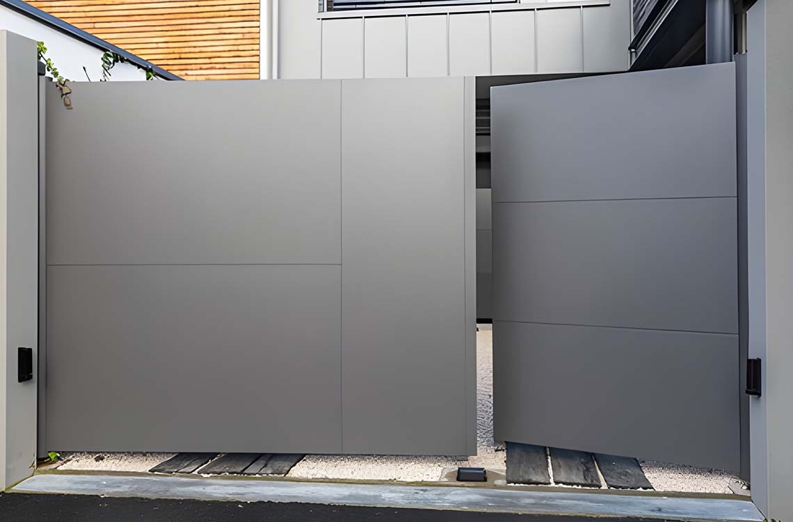 Gray metal privacy gate panels closing between light gray walls above paving