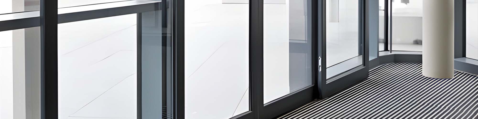 Dark framed glass partition wall above striped carpet flooring with white column