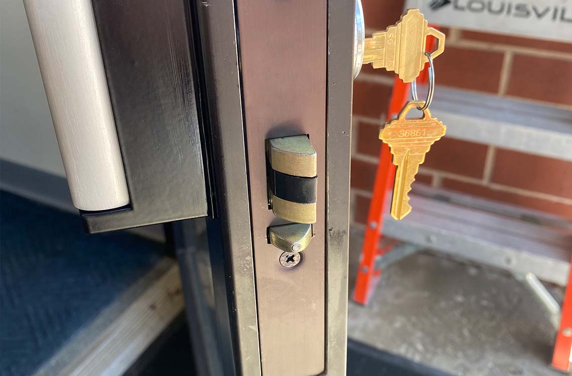 Keys on a hook beside a steel door edge latch and lock cylinder