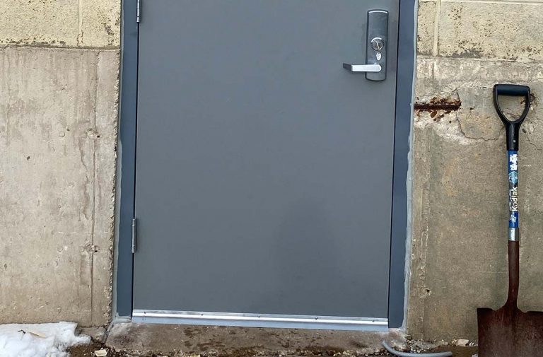 Gray steel exterior door with lever handle set in concrete block wall