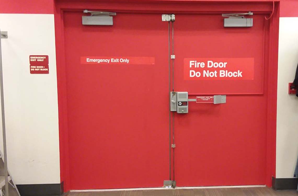 Red double fire doors with Do Not Block and Emergency Exit Only signage