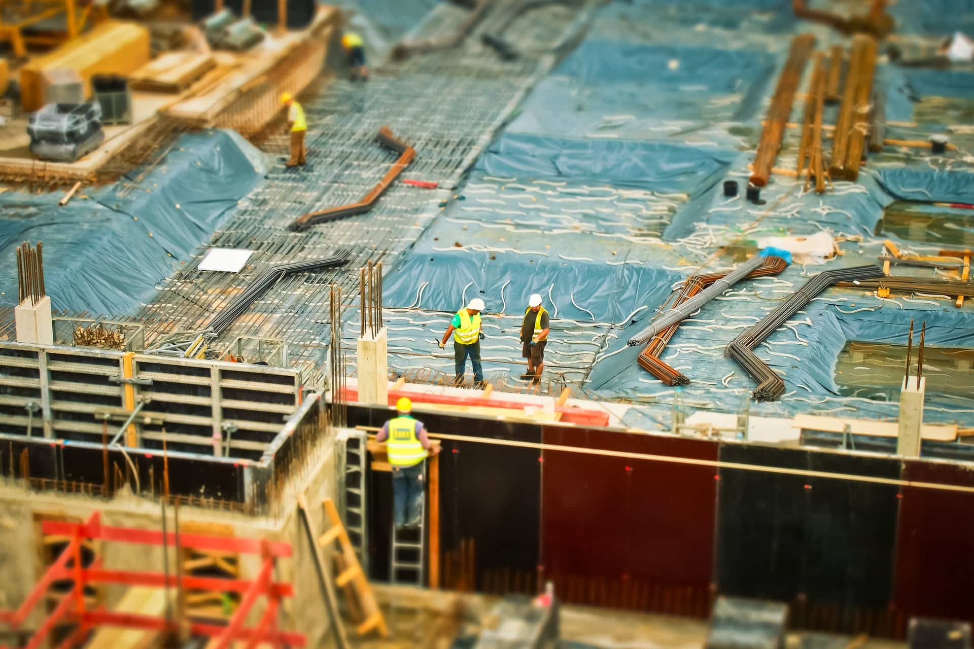 Tilt shift view of a construction site with rebar mats blue tarps and workers