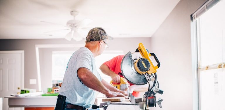 Man using a yellow miter saw on a workbench inside a home