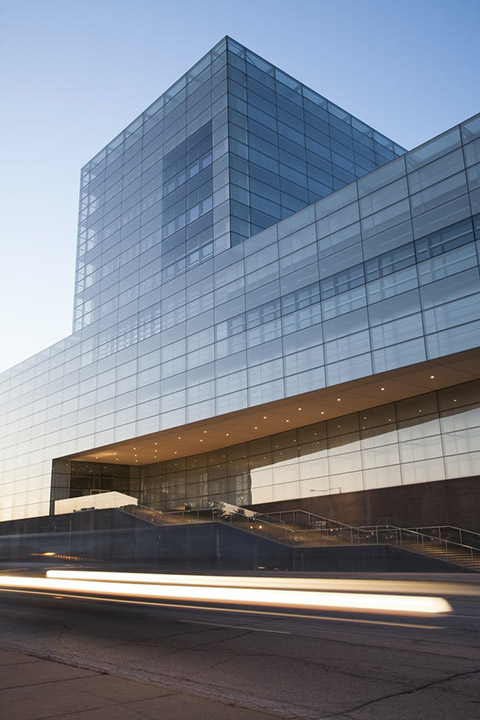 Glass curtain wall office building with lit entrance canopy at dusk