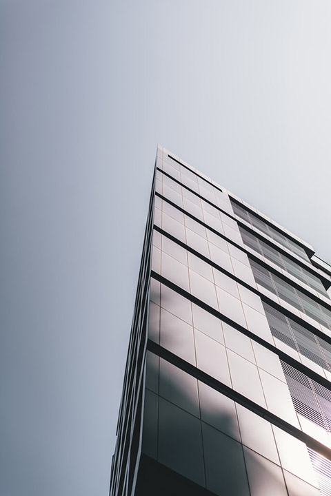 Metal panel building facade seen from below against gray overcast sky